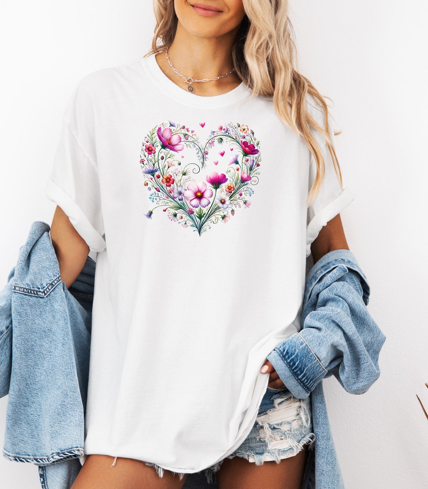 Person wearing a white t-shirt with a wildflower boho heart design, standing against a white background.