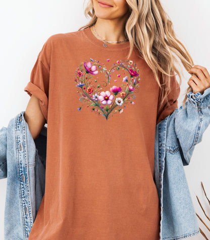 Person wearing a yam t-shirt with a wildflower boho heart design, standing against a white background.