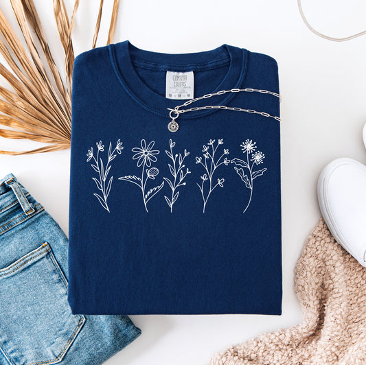True Navy Comfort Colors® t-shirt featuring a minimalist white line art wildflower design across the chest. Simple hand-drawn botanical outlines create a delicate and nature-inspired look, perfect for plant lovers, gardeners, and boho style. Soft, relaxed fit ideal for casual everyday wear.