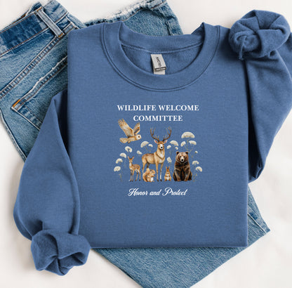 Indigo Blue Gildan sweatshirt featuring a heartwarming “Wildlife Welcome Committee” design with detailed illustrations of woodland animals—deer, bear, owl, fox, rabbit, and more—surrounded by wildflowers. The phrase “Honor and Protect” appears below, promoting love and respect for nature. Perfect for wildlife enthusiasts and outdoor lovers.
