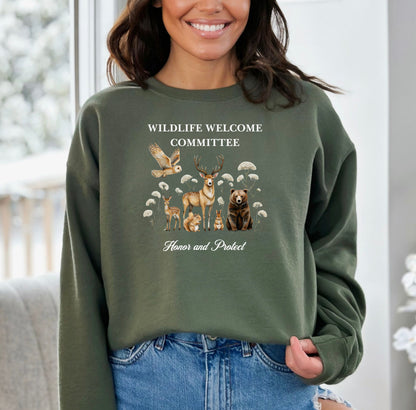 Military Green Gildan sweatshirt featuring a heartwarming “Wildlife Welcome Committee” design with detailed illustrations of woodland animals—deer, bear, owl, fox, rabbit, and more—surrounded by wildflowers. The phrase “Honor and Protect” appears below, promoting love and respect for nature. Perfect for wildlife enthusiasts and outdoor lovers.