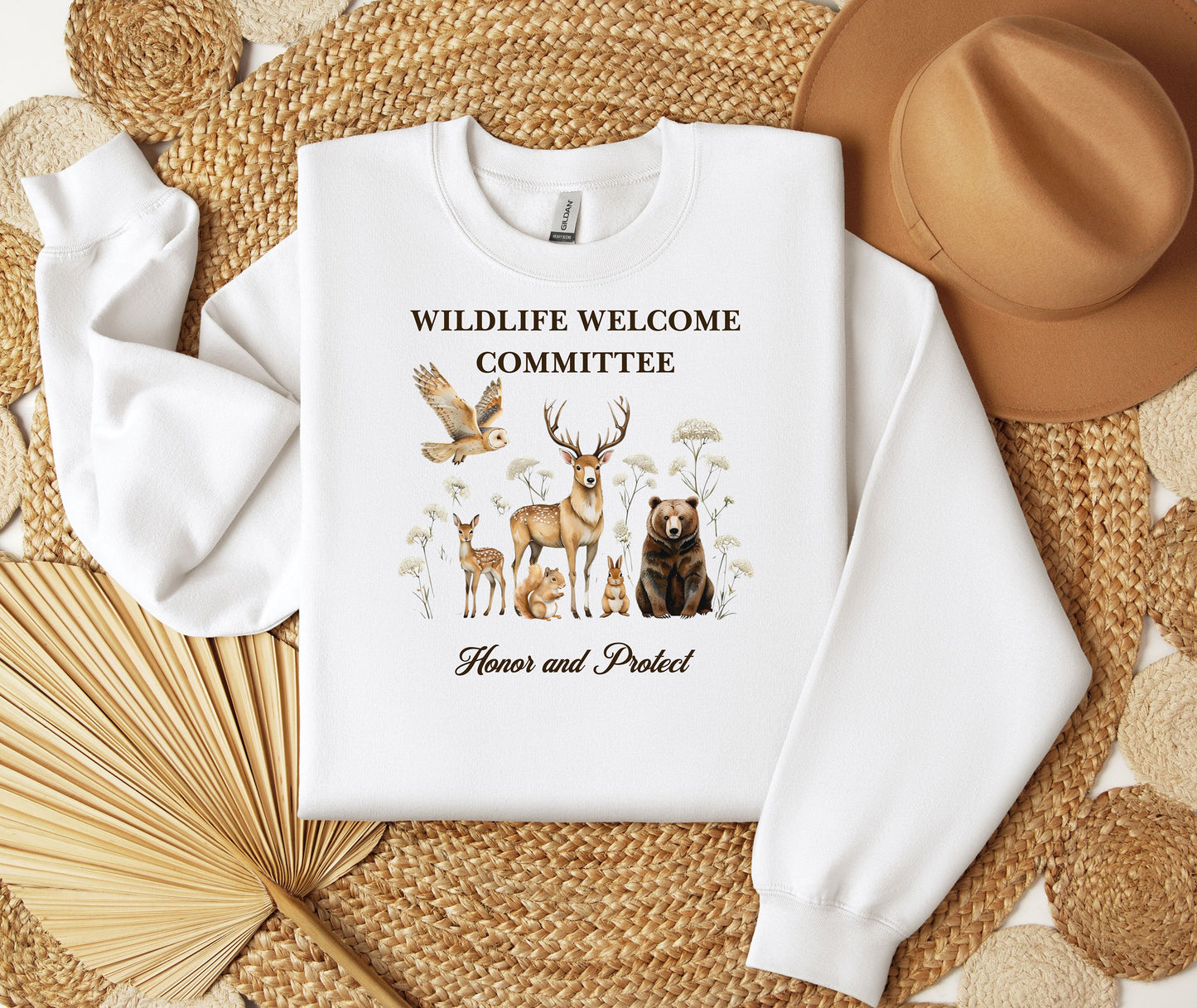 White Gildan sweatshirt featuring a heartwarming “Wildlife Welcome Committee” design with detailed illustrations of woodland animals—deer, bear, owl, fox, rabbit, and more—surrounded by wildflowers. The phrase “Honor and Protect” appears below, promoting love and respect for nature. Perfect for wildlife enthusiasts and outdoor lovers.