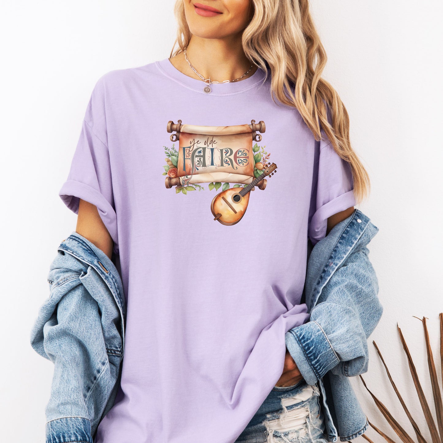 Orchid T-shirt featuring a whimsical Renaissance Faire design with the words “Ye Olde Faire” written on a scroll accented by flowers and greenery, alongside a medieval-style lute. Perfect for festival goers, music lovers, and fans of historical fairs, knights, and old-world charm.