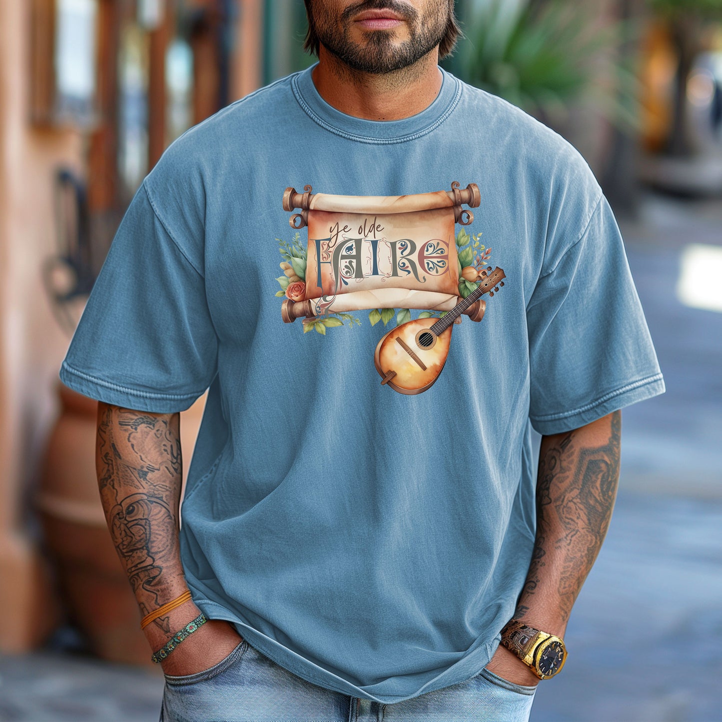 Washed Denim T-shirt featuring a whimsical Renaissance Faire design with the words “Ye Olde Faire” written on a scroll accented by flowers and greenery, alongside a medieval-style lute. Perfect for festival goers, music lovers, and fans of historical fairs, knights, and old-world charm.