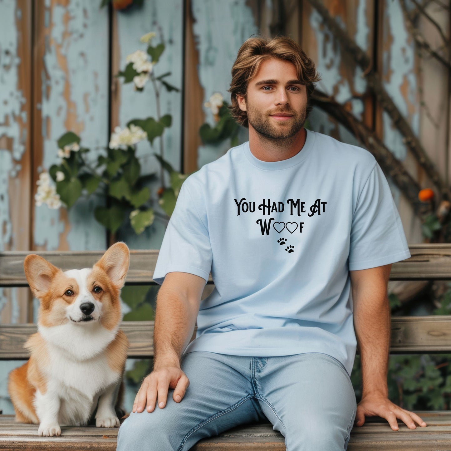 Person wearing a baby blue T-shirts featuring the phrase “You Had Me At Woof” in playful black text. The design includes heart shapes inside the letters and two small paw prints beneath, creating a cute and stylish look perfect for dog lovers and pet owners.