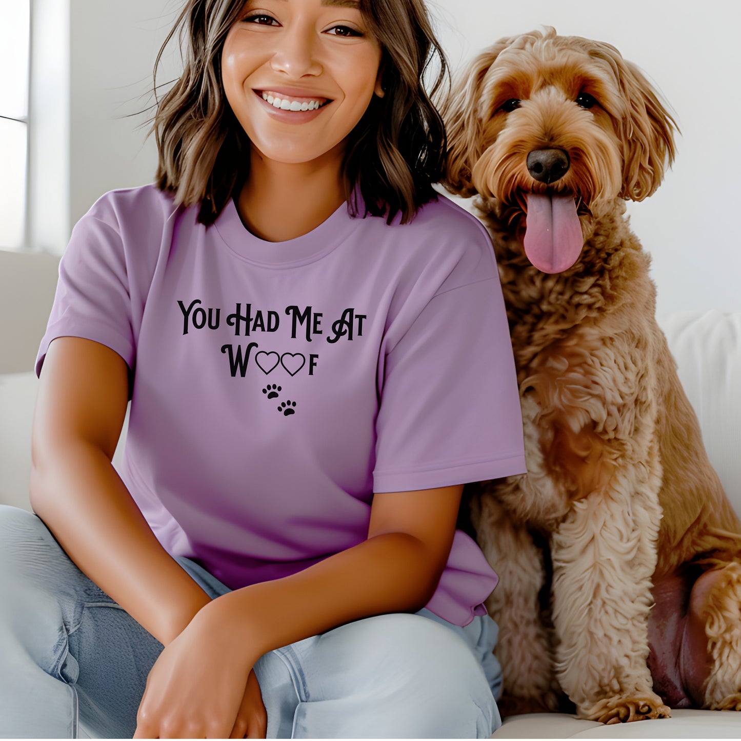 Person wearing a lilac T-shirts featuring the phrase “You Had Me At Woof” in playful black text. The design includes heart shapes inside the letters and two small paw prints beneath, creating a cute and stylish look perfect for dog lovers and pet owners.