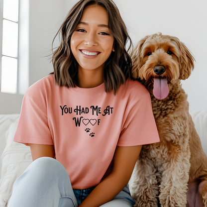 Person wearing a sunset T-shirts featuring the phrase “You Had Me At Woof” in playful black text. The design includes heart shapes inside the letters and two small paw prints beneath, creating a cute and stylish look perfect for dog lovers and pet owners.