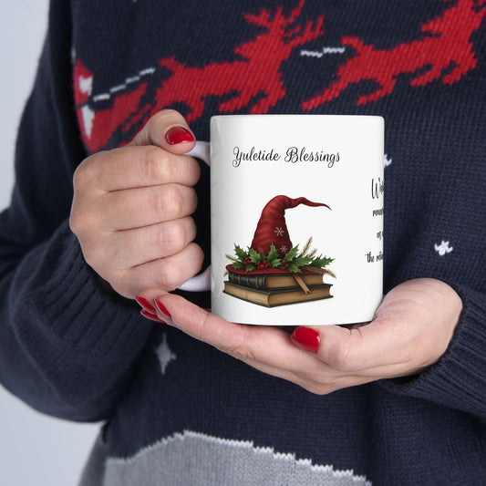 Person holding a ceramic mug with a Yuletide Blessing witch's hat design, wearing a festive sweater.
