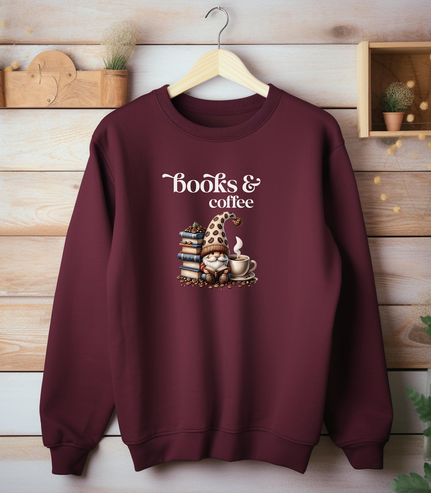 Maroon Gildan sweatshirt featuring an adorable “Books & Coffee” design with a cozy gnome wearing a polka-dot hat, sitting beside a stack of books, a steaming coffee cup, and scattered coffee beans. A charming and whimsical design perfect for book lovers, coffee enthusiasts, and fall vibes.