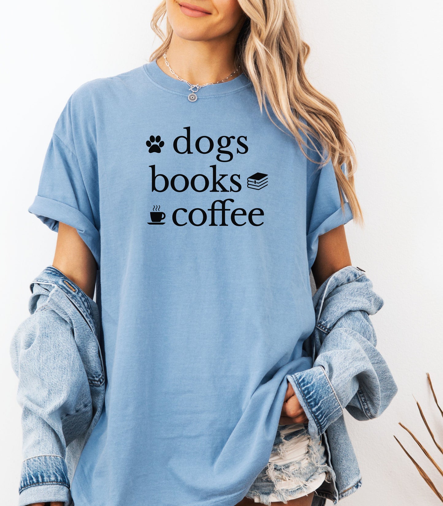 Black graphic design on a Washed Denimn t-shirt featuring the phrase “Dogs, Books, Coffee” in bold, playful lettering. Decorative icons of a dog paw, stacked books, and a steaming coffee cup enhance the cozy, laid-back vibe—perfect for dog lovers, bookworms, and caffeine enthusiasts alike.