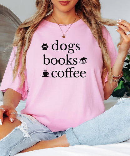 Black graphic design on a blossom pink t-shirt featuring the phrase “Dogs, Books, Coffee” in bold, playful lettering. Decorative icons of a dog paw, stacked books, and a steaming coffee cup enhance the cozy, laid-back vibe—perfect for dog lovers, bookworms, and caffeine enthusiasts alike.