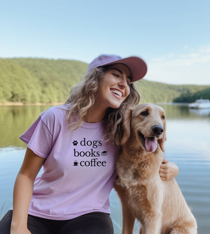 Black graphic design on an orchid t-shirt featuring the phrase “Dogs, Books, Coffee” in bold, playful lettering. Decorative icons of a dog paw, stacked books, and a steaming coffee cup enhance the cozy, laid-back vibe—perfect for dog lovers, bookworms, and caffeine enthusiasts alike.