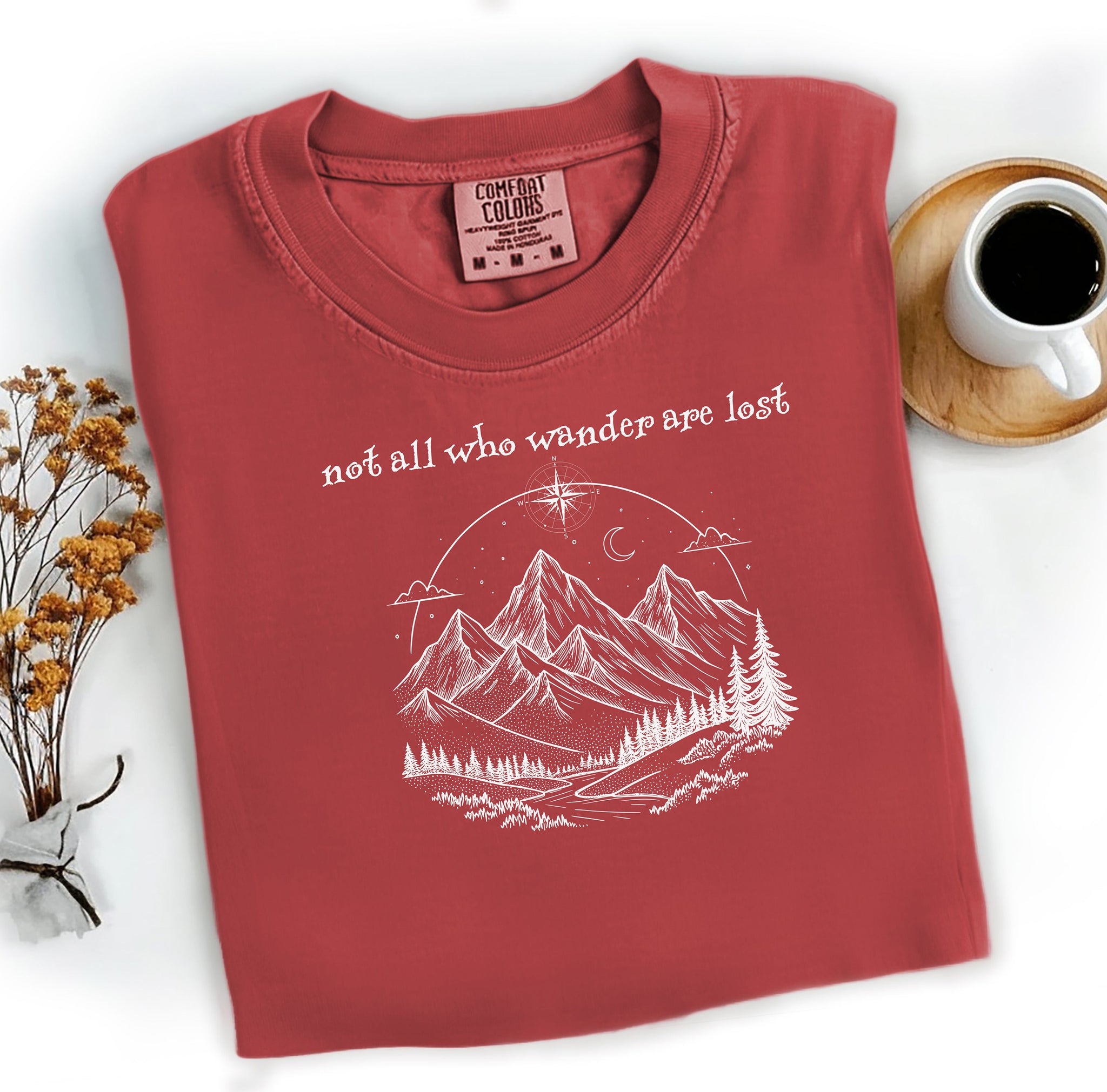 Not All Who Wander Are Lost T-shirt featuring an artistic nature scene with hand-drawn mountains, pine trees, a winding trail, and a starry sky with a crescent moon. This adventurous design, printed on a soft, chili comfortable unisex tee, inspires exploration, travel, and a free-spirited lifestyle. Perfect for hikers, nature lovers, and wanderers who embrace the journey and find peace in the great outdoors.