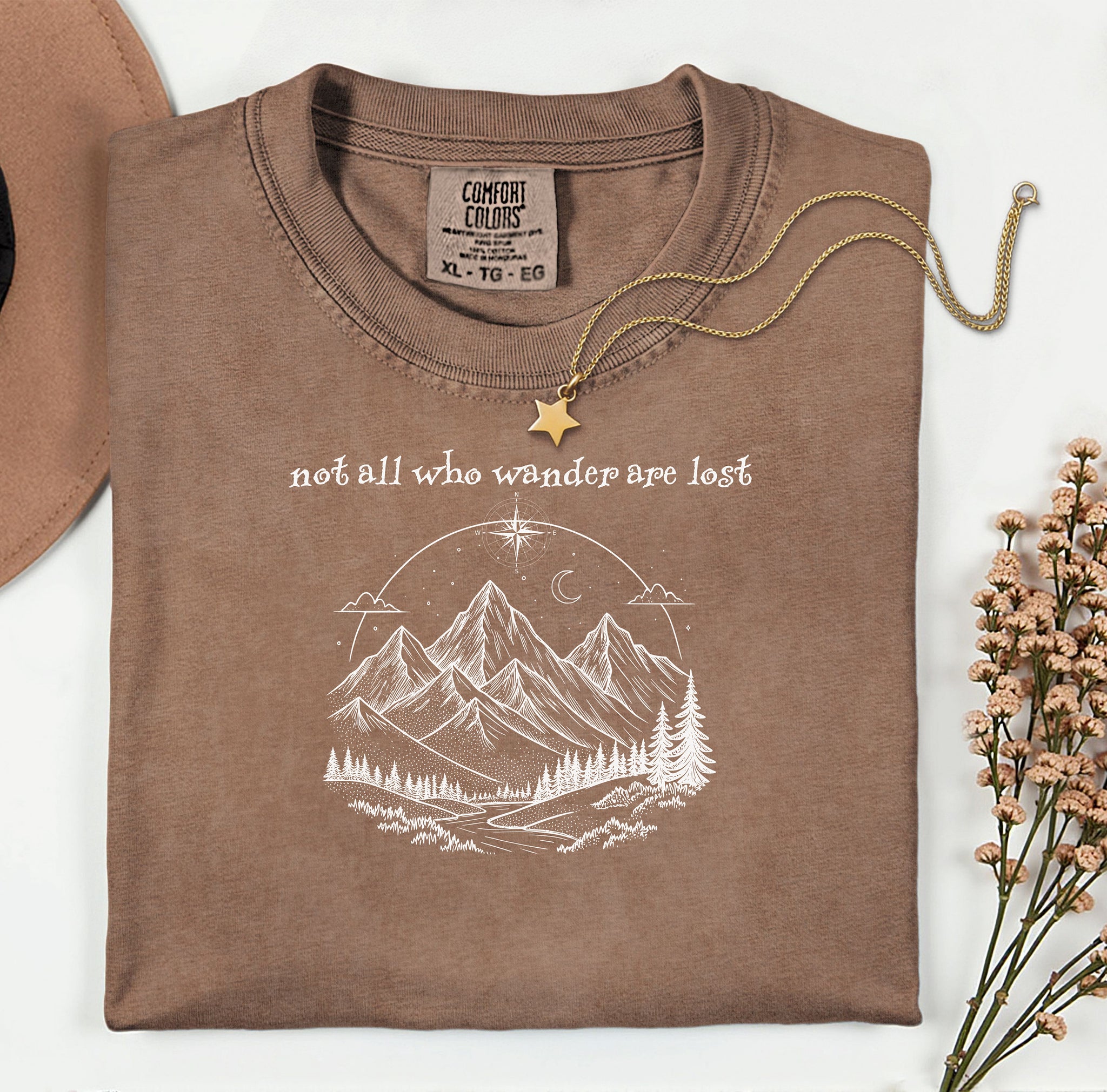 Not All Who Wander Are Lost T-shirt featuring an artistic nature scene with hand-drawn mountains, pine trees, a winding trail, and a starry sky with a crescent moon. This adventurous design, printed on a soft, espresso comfortable unisex tee, inspires exploration, travel, and a free-spirited lifestyle. Perfect for hikers, nature lovers, and wanderers who embrace the journey and find peace in the great outdoors.