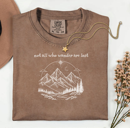 Not All Who Wander Are Lost T-shirt featuring an artistic nature scene with hand-drawn mountains, pine trees, a winding trail, and a starry sky with a crescent moon. This adventurous design, printed on a soft, espresso comfortable unisex tee, inspires exploration, travel, and a free-spirited lifestyle. Perfect for hikers, nature lovers, and wanderers who embrace the journey and find peace in the great outdoors.
