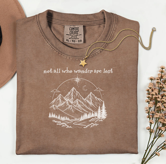 Not All Who Wander Are Lost T-shirt featuring an artistic nature scene with hand-drawn mountains, pine trees, a winding trail, and a starry sky with a crescent moon. This adventurous design, printed on a soft, espresso comfortable unisex tee, inspires exploration, travel, and a free-spirited lifestyle. Perfect for hikers, nature lovers, and wanderers who embrace the journey and find peace in the great outdoors.