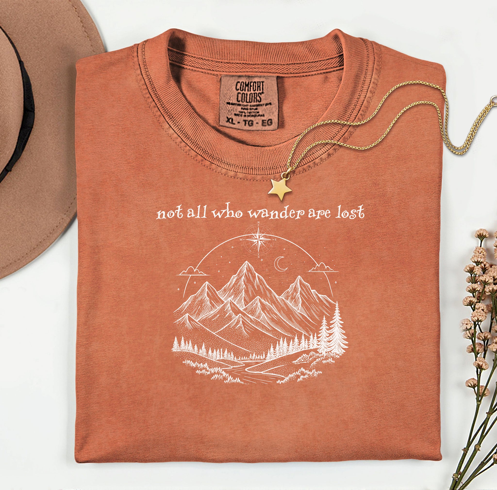 Not All Who Wander Are Lost T-shirt featuring an artistic nature scene with hand-drawn mountains, pine trees, a winding trail, and a starry sky with a crescent moon. This adventurous design, printed on a soft, yam comfortable unisex tee, inspires exploration, travel, and a free-spirited lifestyle. Perfect for hikers, nature lovers, and wanderers who embrace the journey and find peace in the great outdoors.